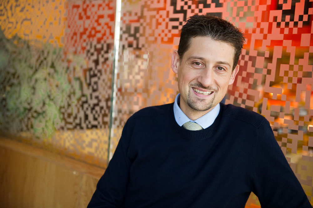 Faculty member, Emilio Baglietto, infront of a glass wall with digital dot pattern, MIT